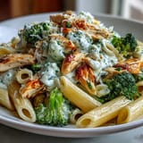A close-up of High Protein Rotisserie Chicken Broccoli Pasta garnished with fresh parsley and extra Parmesan, with garlic and lemon zest adding aroma.  