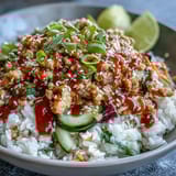 A close-up of Bang Bang Ground Turkey Rice Bowls garnished with sesame seeds, scallions, and fresh lime wedges.