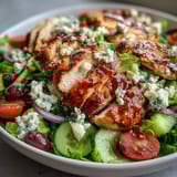 Colorful Mediterranean salad with grilled chicken, crisp cucumbers, tomatoes, and olives in a tangy dressing.  