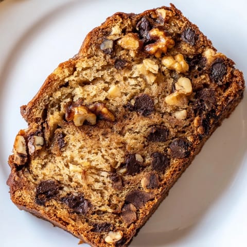 Slices of moist Banana Bread topped with melting butter and toasted walnuts, served on a rustic plate with a coffee mug.