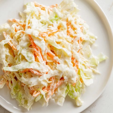The classic Coleslaw is tossed with a tangy mayonnaise dressing and sprinkled with celery seed, ready for a picnic.