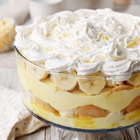 Chilled Southern banana pudding in a glass dish reveals layers of cookies, custard, and ripe bananas.