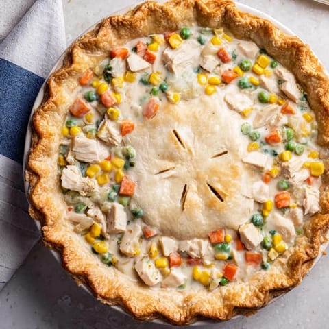 Golden-baked Chicken Pot Pie with a flaky crust is emerging from the oven, bubbling with a creamy chicken and vegetable filling.