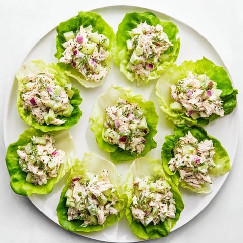 Juicy shredded chicken mixed with chopped pickles, red onion, and a creamy dressing in a Dill Pickle Chicken Salad Lettuce Cup served on a platter.