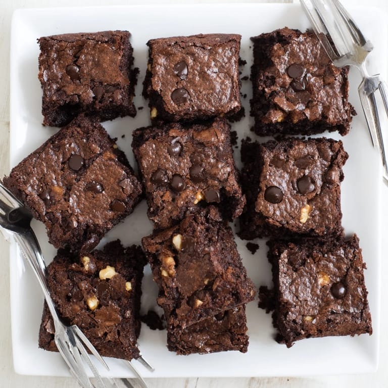 Warm, freshly baked brownies arranged in squares on parchment, perfect for sharing with vanilla ice cream.
