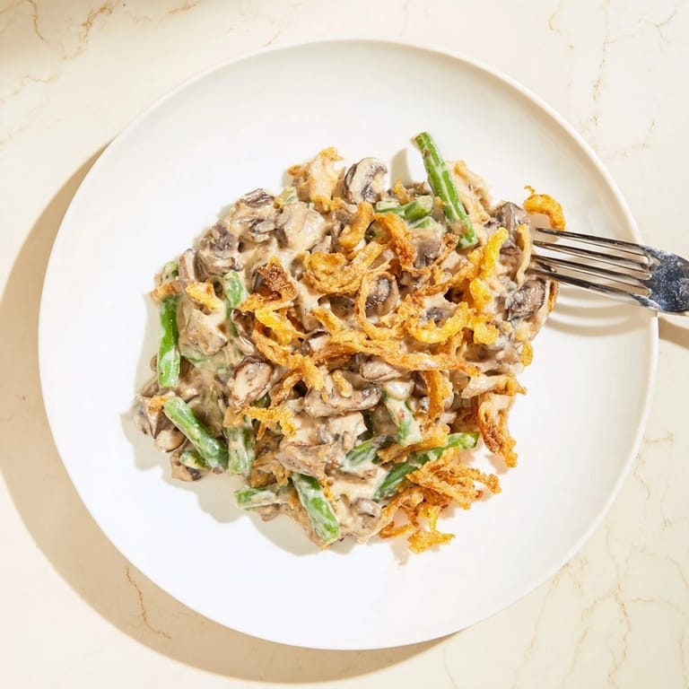 Spoon serving Green Bean Casserole onto a plate, paired with roasted turkey and herbs for a festive dinner.