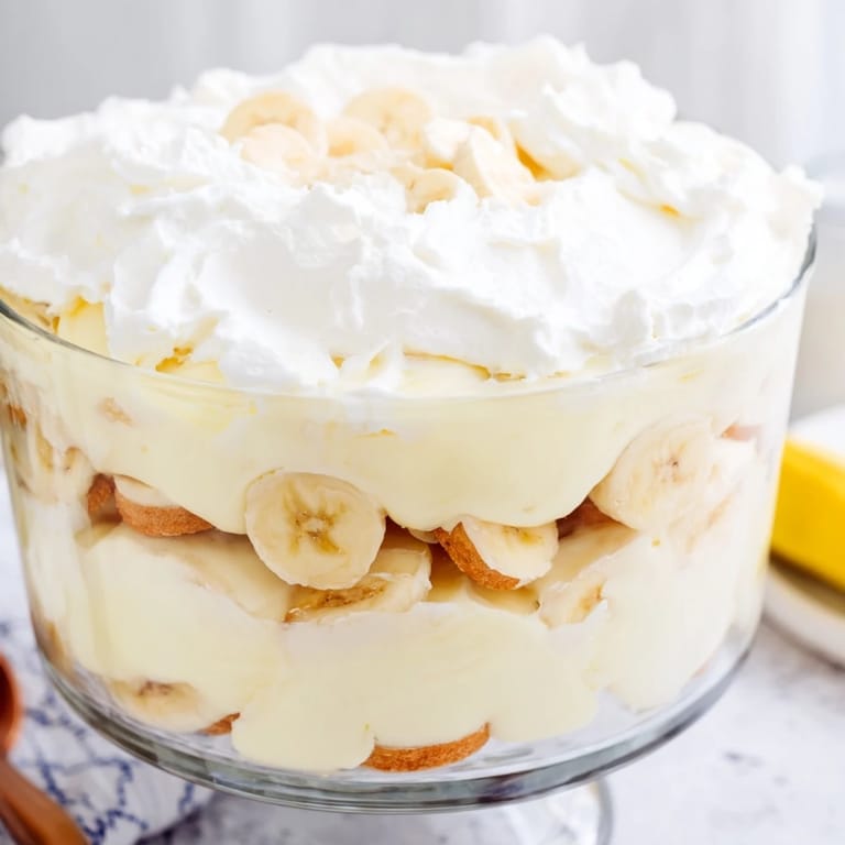 Homemade banana pudding dessert with fluffy whipped cream topping and vanilla wafers, ready to serve chilled.