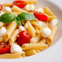 Juicy cherry tomatoes and creamy mozzarella pearls nestle with fragrant basil in this vibrant Caprese Salad Pasta, tossed in olive oil.  