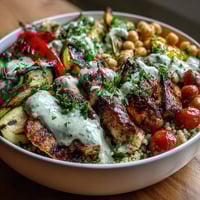 Juicy grilled chicken and charred Mediterranean vegetables rest on fluffy quinoa, topped with creamy tzatziki and crumbled feta.