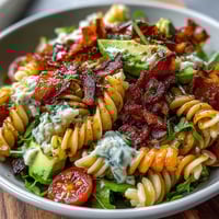 Creamy BLT Pasta Salad with Bacon and Avocado in a rustic bowl, garnished with fresh herbs and crispy bacon bits.
